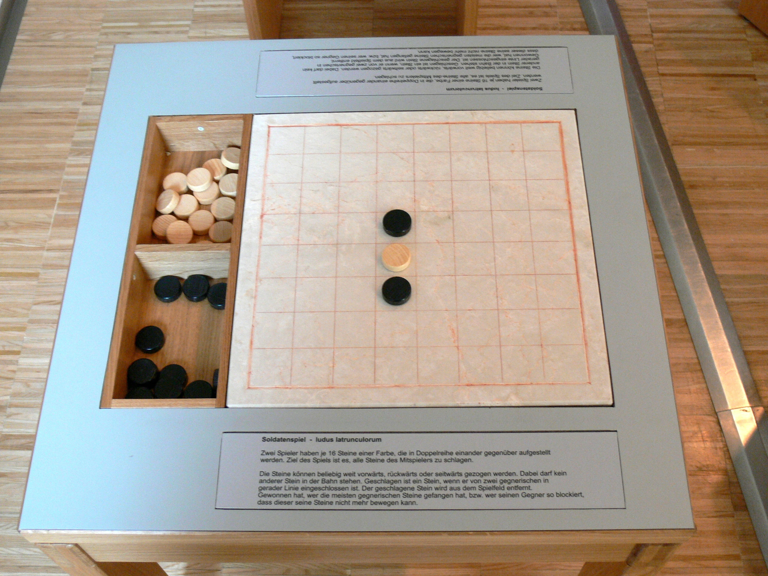 Ricostruzione museale del ludus latrunculorum, il gioco da tavolo dei soldati romani, con scacchiera e pedine.